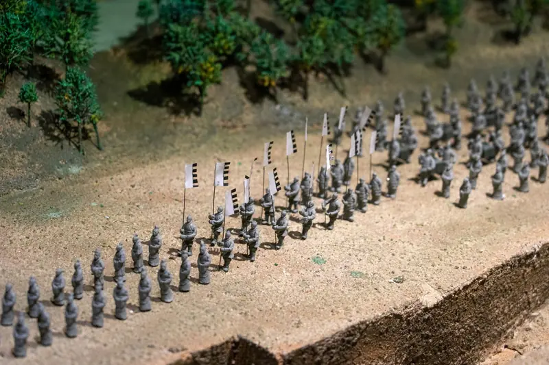 Close-up of a miniature army model with flags, depicted in a diorama scene