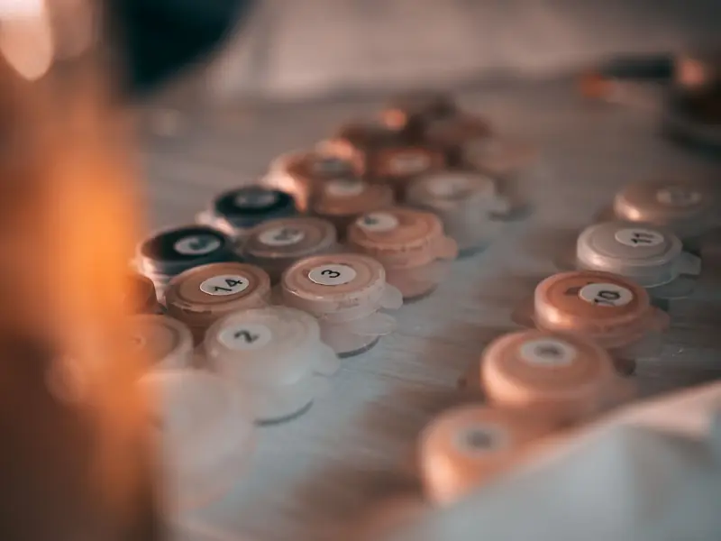 Artistic close-up of numbered paint pots on a table, ideal for painting by numbers enthusiasts