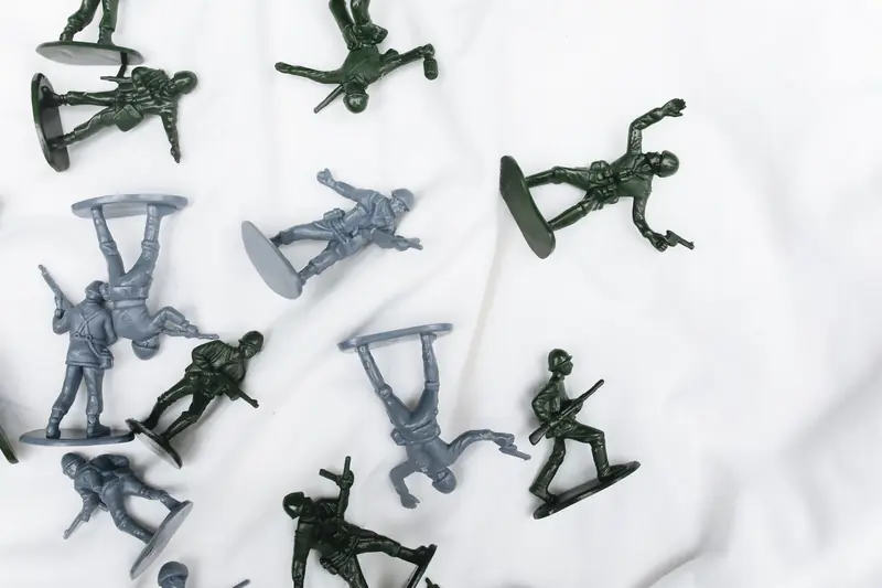 Plastic army figurines in various poses on white surface