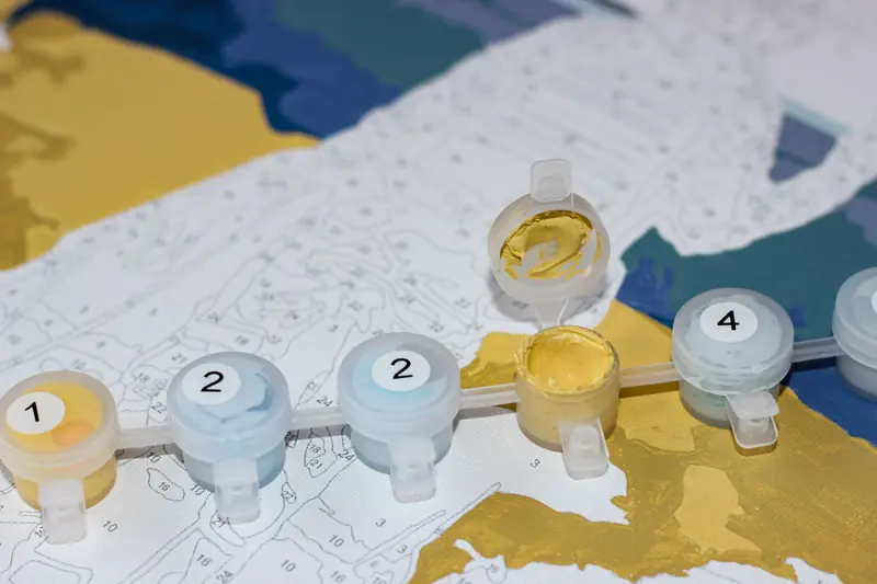 Close-up of paint by numbers art project with open paint pots and color-coded sections