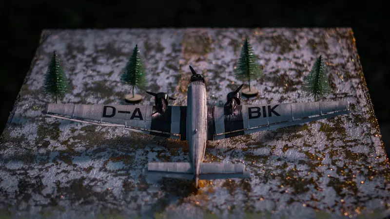 Close-up of a miniature airplane model surrounded by tiny trees on a textured, snowy surface