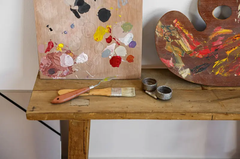 An artist's palette and brushes on a rustic wooden table, showcasing vibrant paint colors