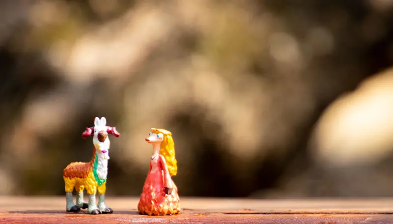 Playful miniature goat and whimsical character figurines on a rustic surface