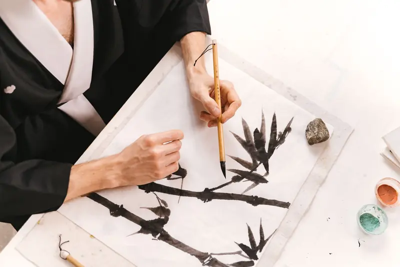 An artistic session capturing a person painting bamboo with a traditional Japanese ink brush on paper