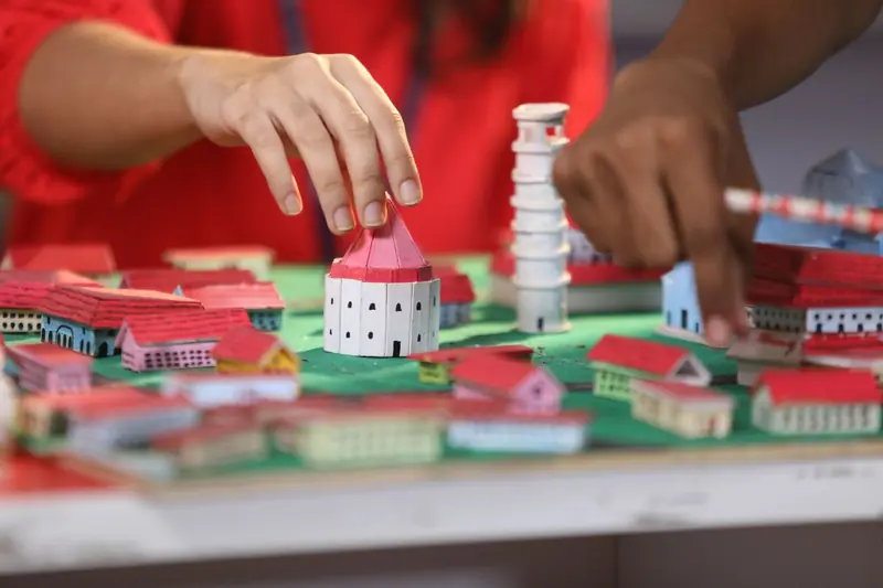 Hands engaging with a colorful miniature town model, focusing on creativity and craftsmanship