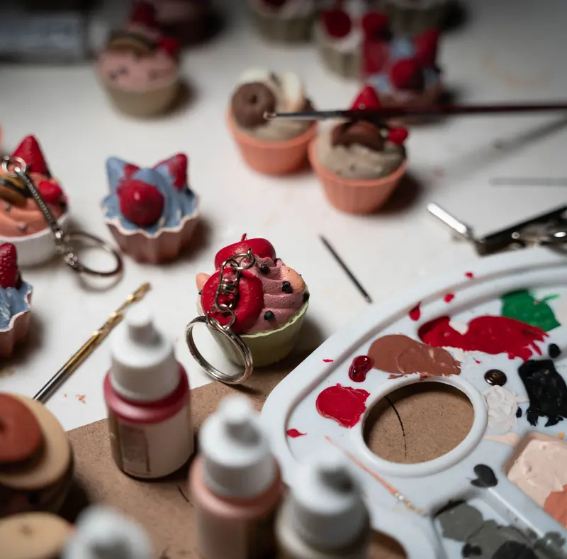 Close-up of miniature food crafting process with paint palette and tools
