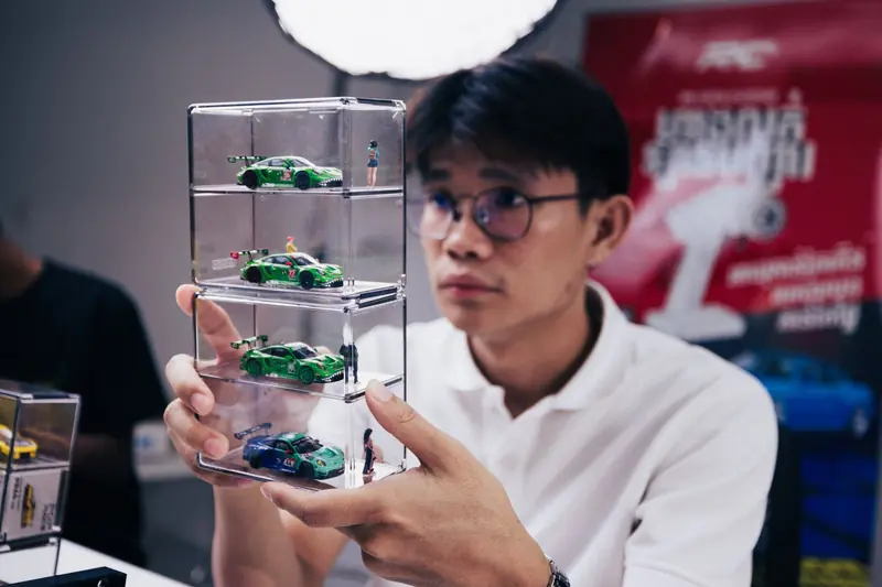 Man showcasing scale model cars in a stackable display case in Phnom Penh