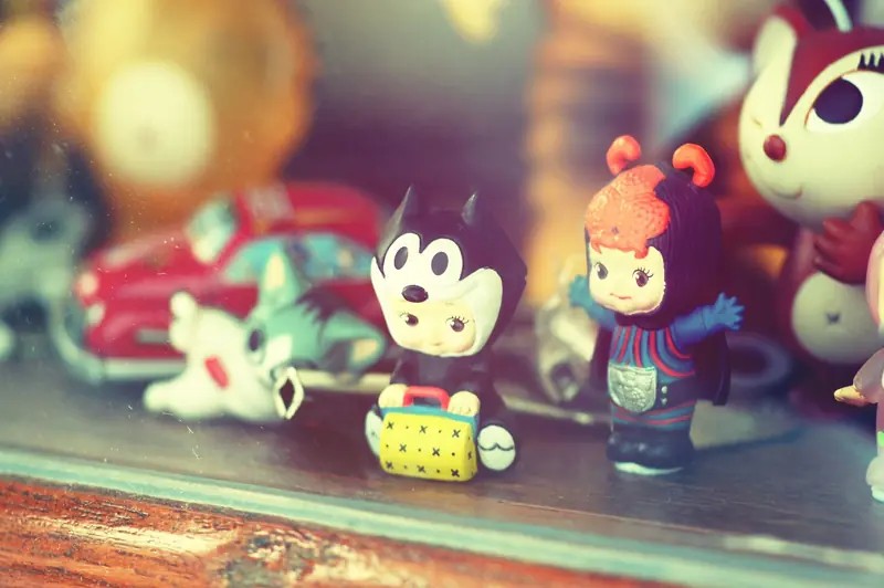 Close-up of vintage toy figurines on a wooden shelf inside a glass display case