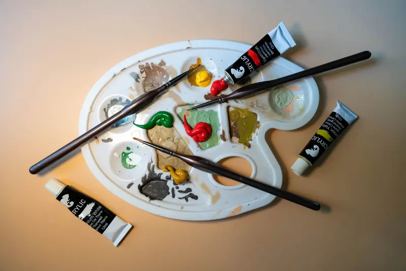 Artistic setup of a palette with acrylic paint tubes and brushes, perfect for creative inspiration