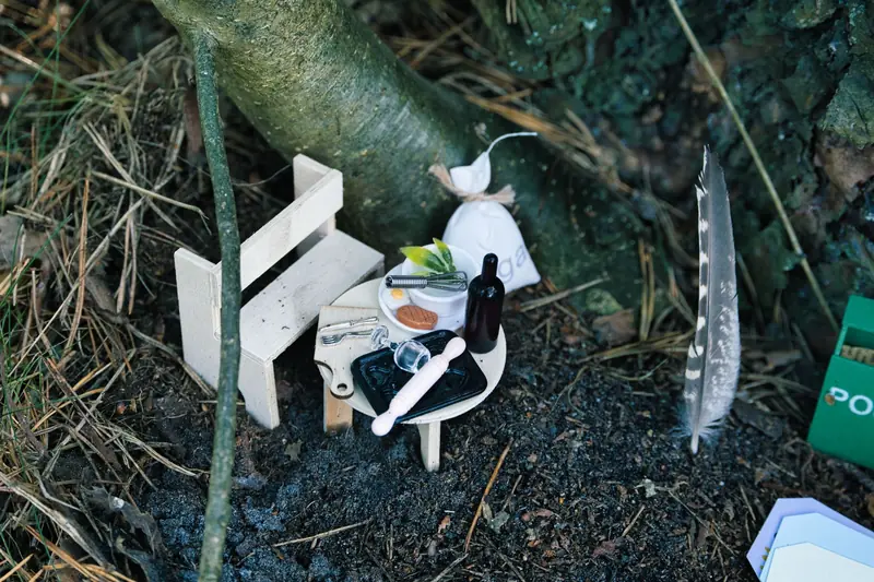 Miniature scene with a small table and bench setup outdoors at the base of a tree