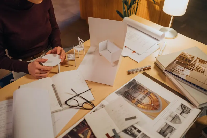Architect reviewing a miniature model design on a desk full of sketches and plans