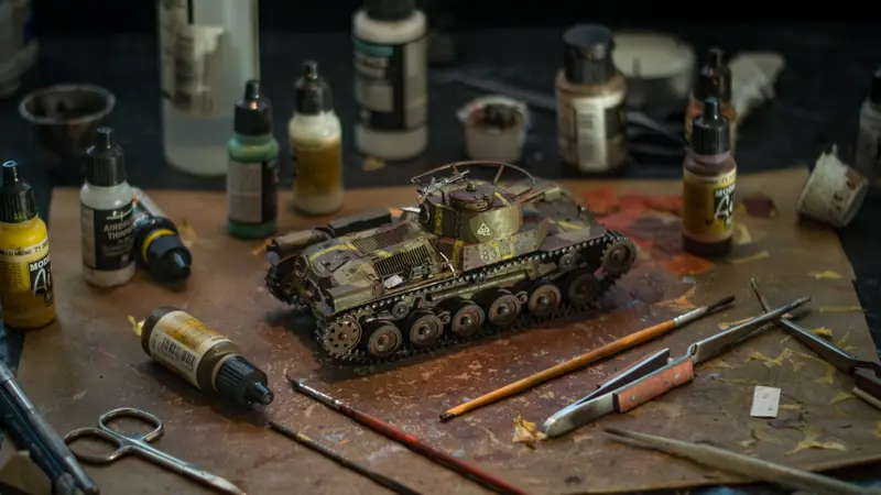 High-quality model tank surrounded by various painting supplies for a realistic diorama